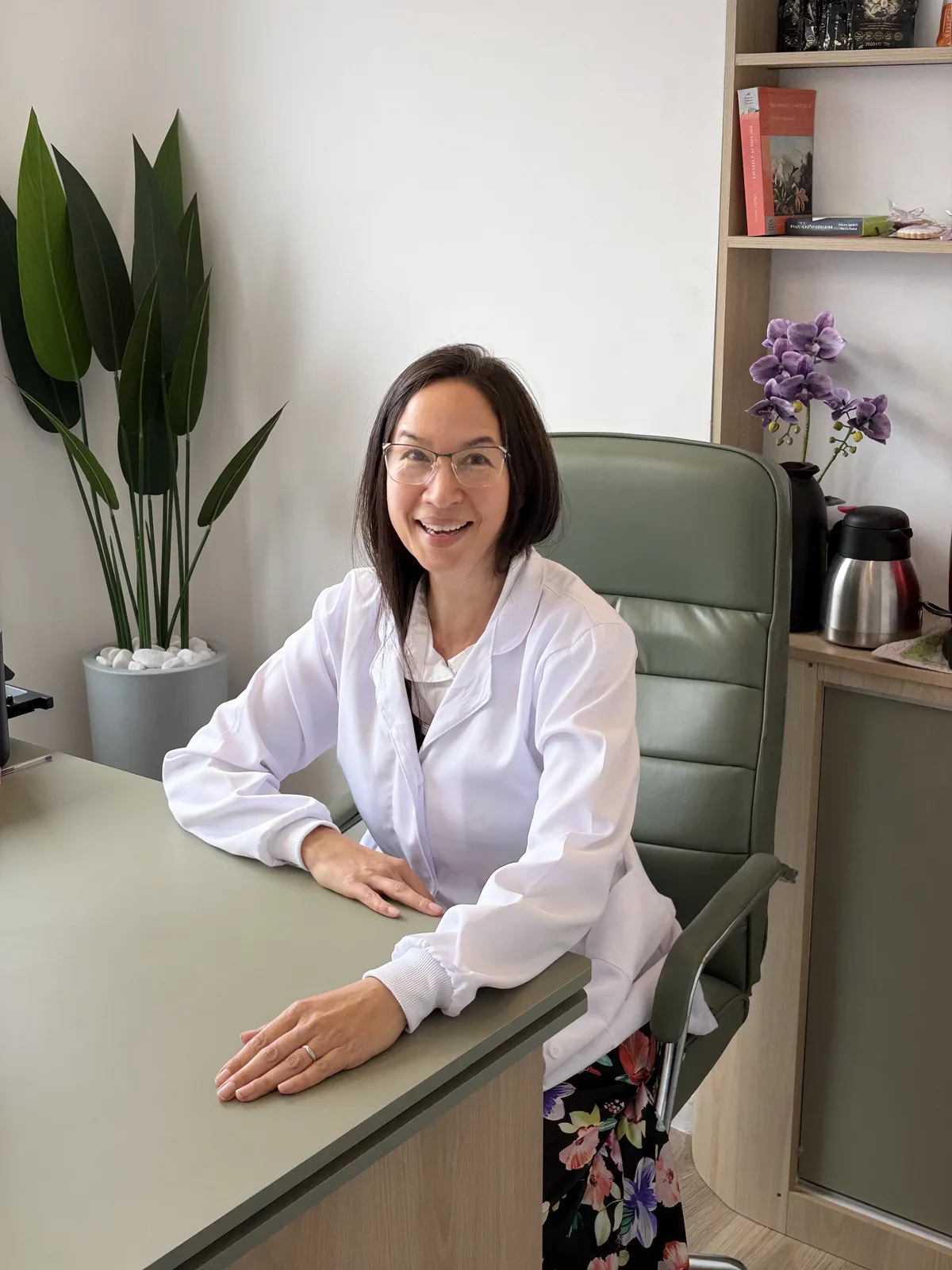 Nutricionista à mesa no consultório Nutrida, com plantas e detalhes em verde e lavanda